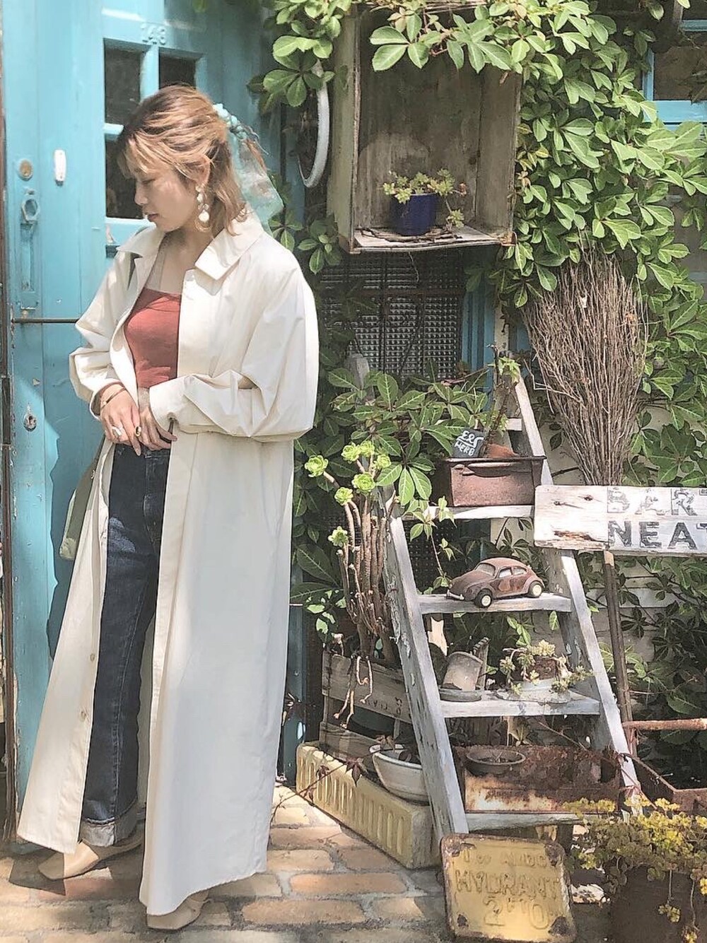 ホワイト系のトレンチコート、ブルー系のデニムパンツ、オレンジ系のキャミソールを着用したレディースの夏コーディネートの1枚目の写真