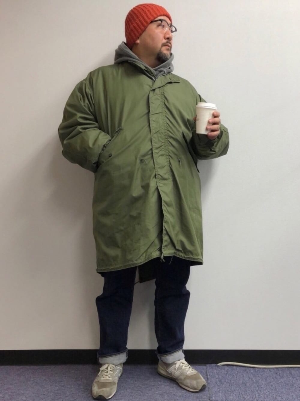 グリーン系のミリタリージャケット、グレー系のパーカー、ブルー系のデニムパンツを着用したメンズの春コーディネートの1枚目の写真
