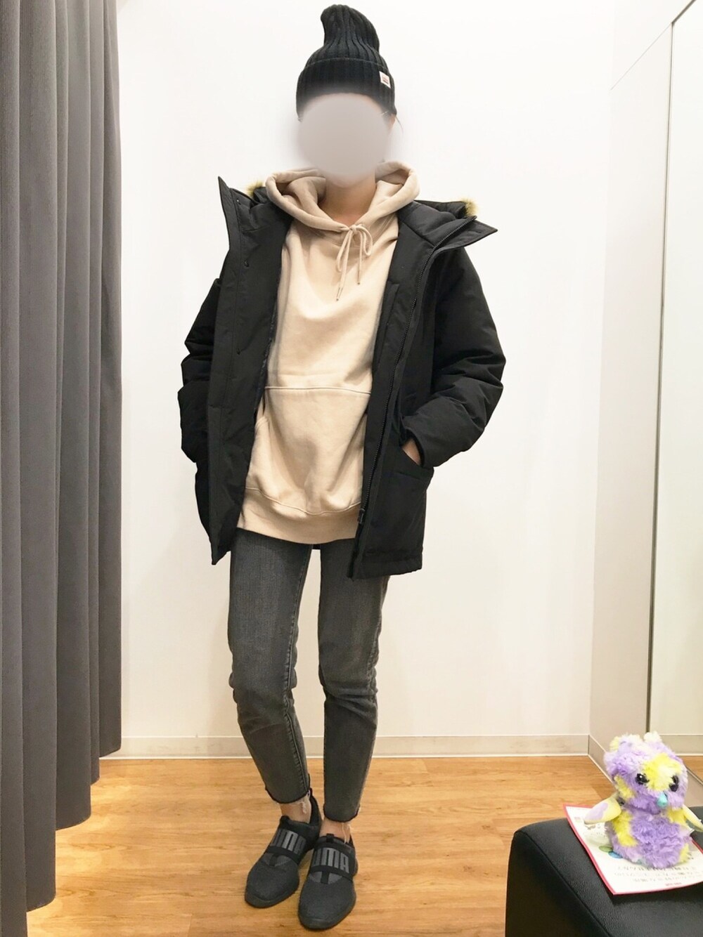 ベージュ系のパーカー、ブラック系のダウンベスト、ブラック系のデニムパンツを着用したレディースの冬コーディネートの1枚目の写真