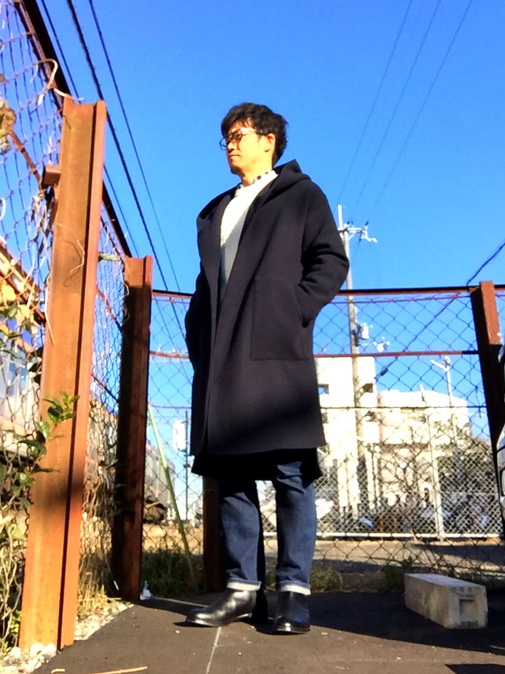 ホワイト系のニット/セーター、ブルー系のデニムパンツ、ブルー系のチェスターコートを着用したメンズの冬コーディネートの1枚目の写真