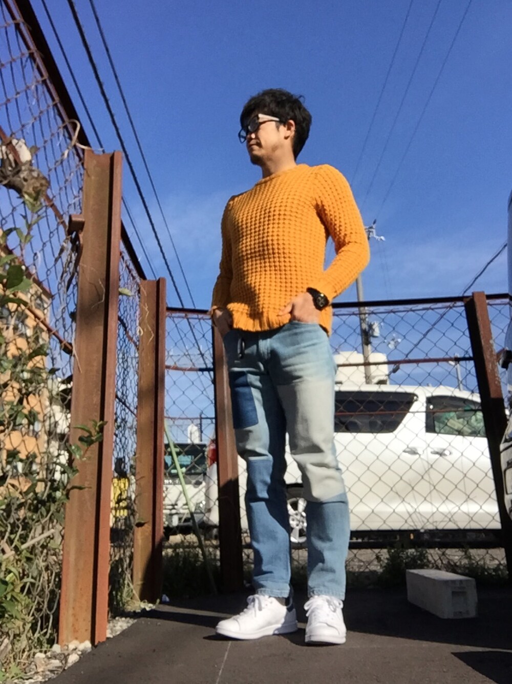 オレンジ系のニット/セーター、ブルー系のデニムパンツを着用したメンズの冬コーディネートの1枚目の写真