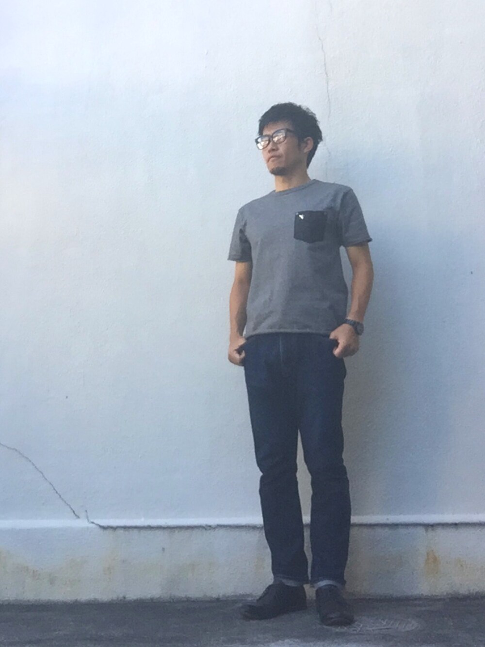 ブラック系のTシャツ/カットソー、ブルー系のデニムパンツ、ブラック系のドレスシューズを着用したメンズの秋コーディネートの1枚目の写真