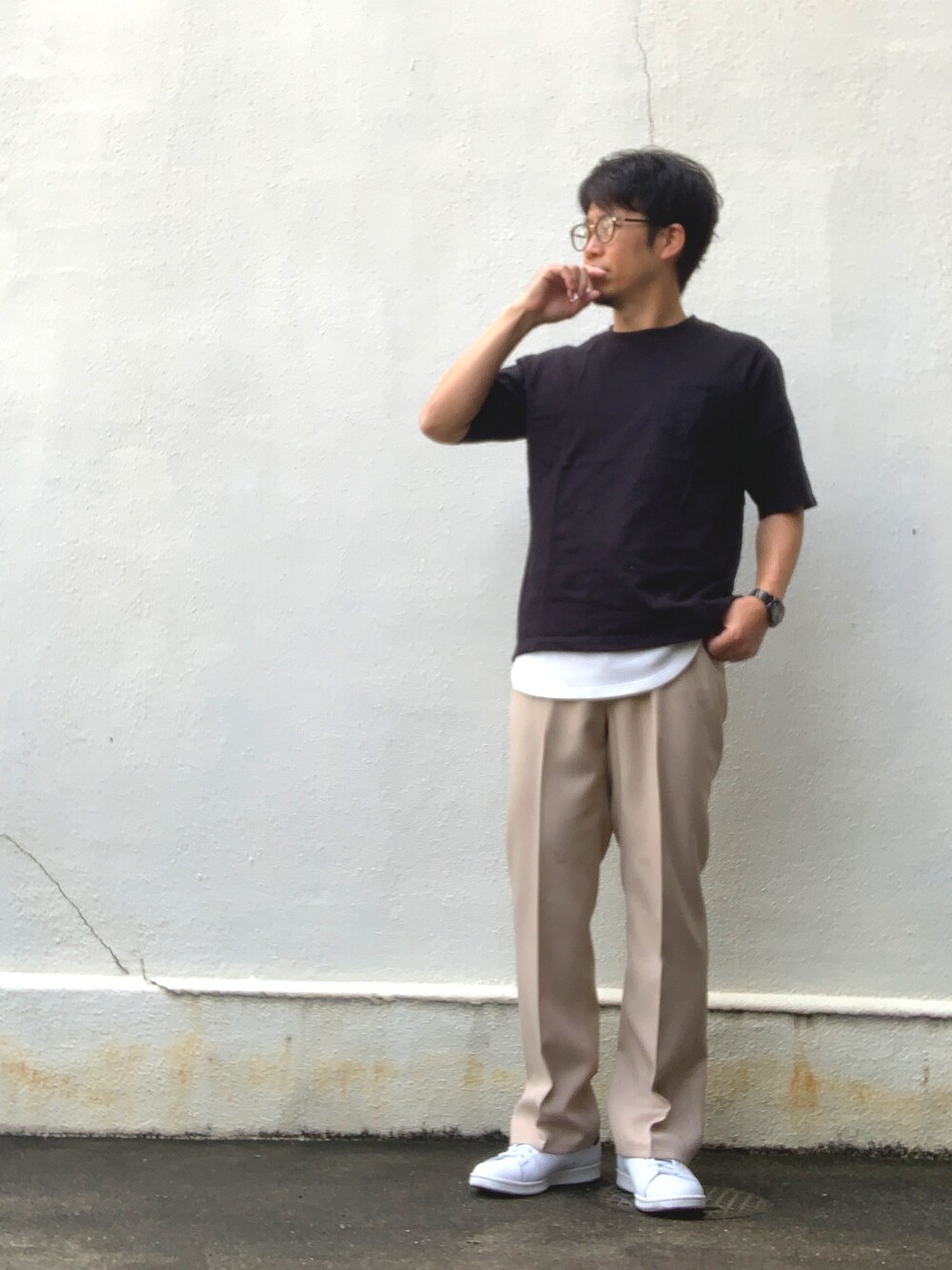 ベージュ系のスラックス、ブラック系のTシャツ/カットソー、ホワイト系のスニーカーを着用したメンズの夏コーディネートの1枚目の写真
