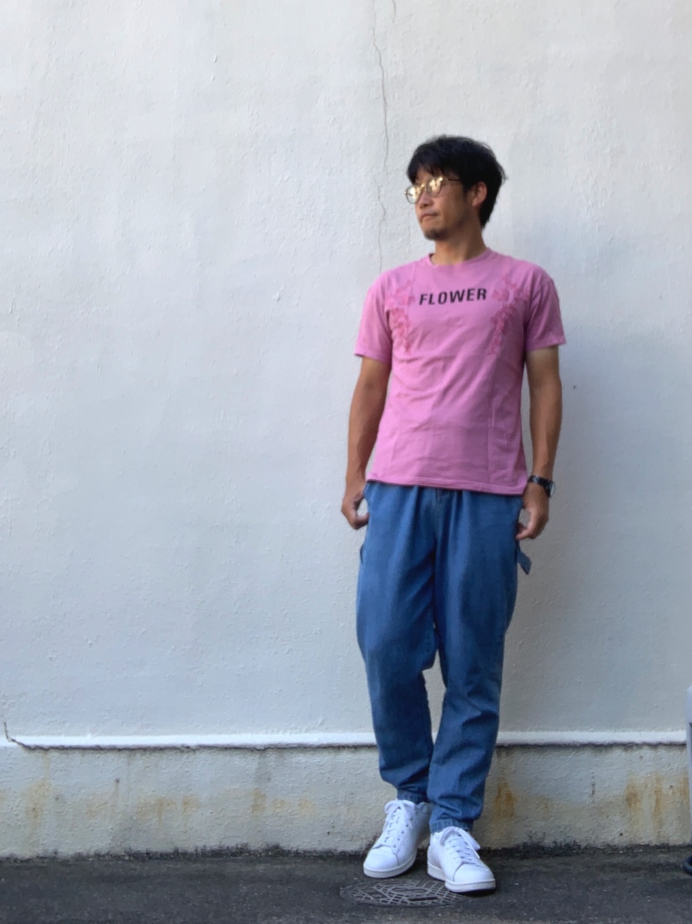 ピンク系のTシャツ/カットソー、ブルー系のデニムパンツ、ホワイト系のスニーカーを着用したメンズの秋コーディネートの1枚目の写真