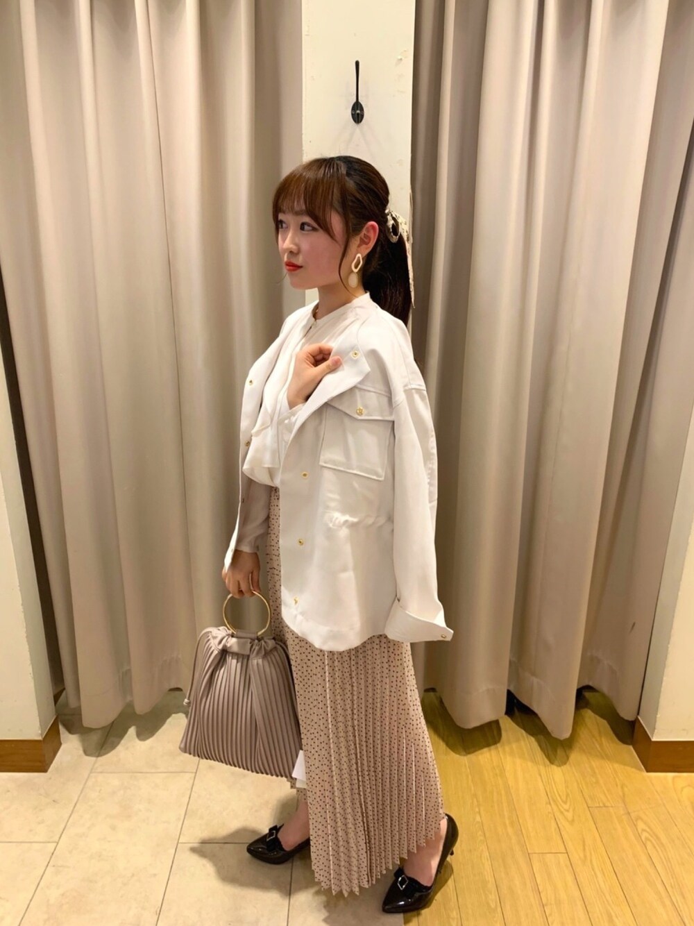 ホワイト系のノーカラージャケット、ピンク系のスカート、グレー系のトートバッグを着用したレディースの春コーディネートの1枚目の写真