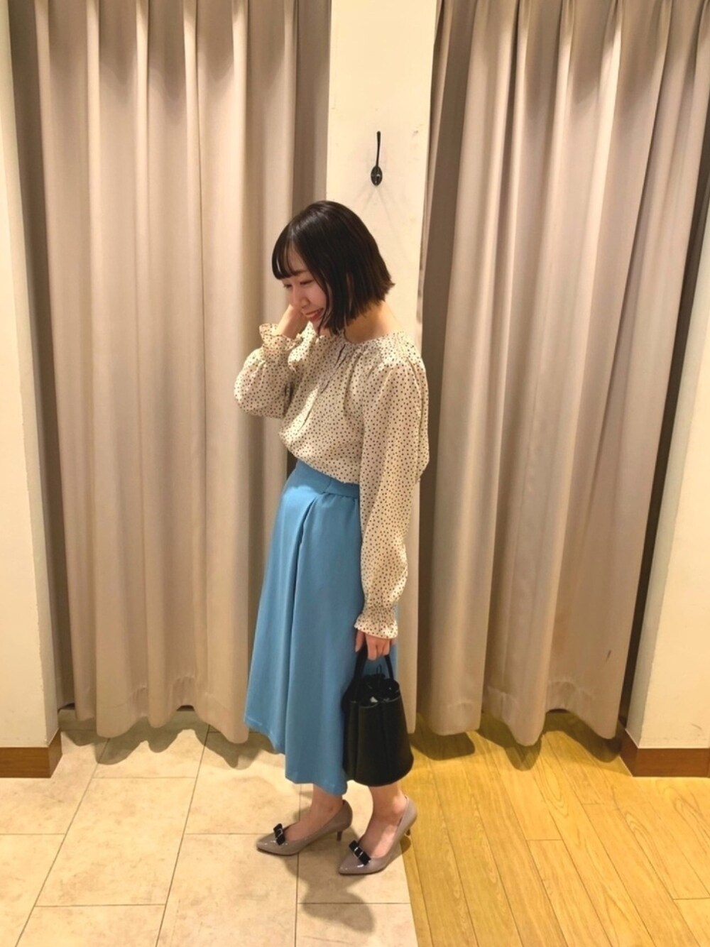 ベージュ系のシャツ/ブラウス、ブルー系のスカート、ブラック系のショルダーバッグを着用したレディースの春コーディネートの1枚目の写真