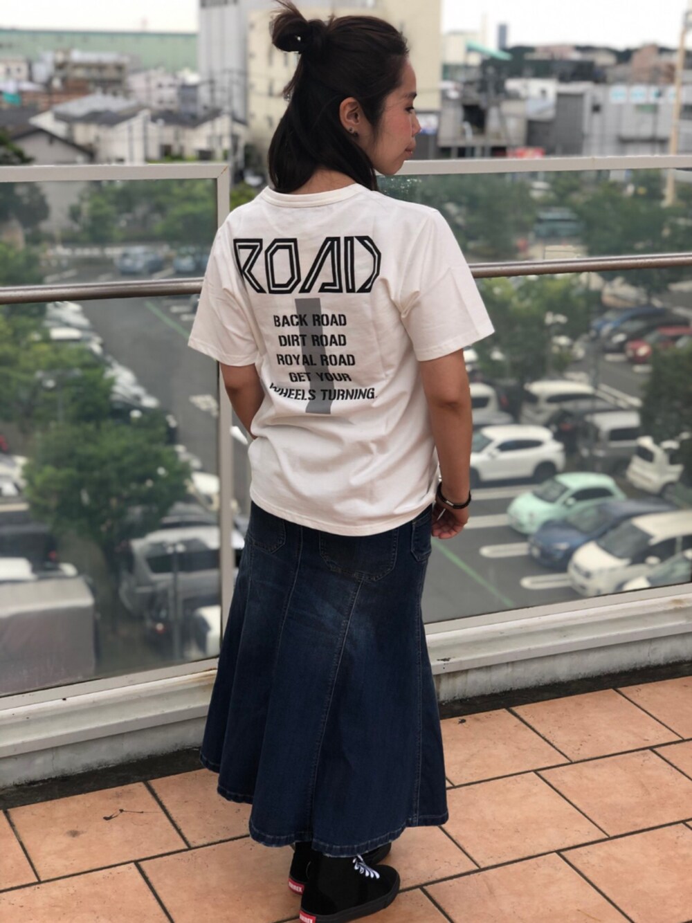 ブラック系のスニーカー、ブルー系のデニムスカート、ホワイト系のTシャツ/カットソーを着用したレディースの夏コーディネートの1枚目の写真