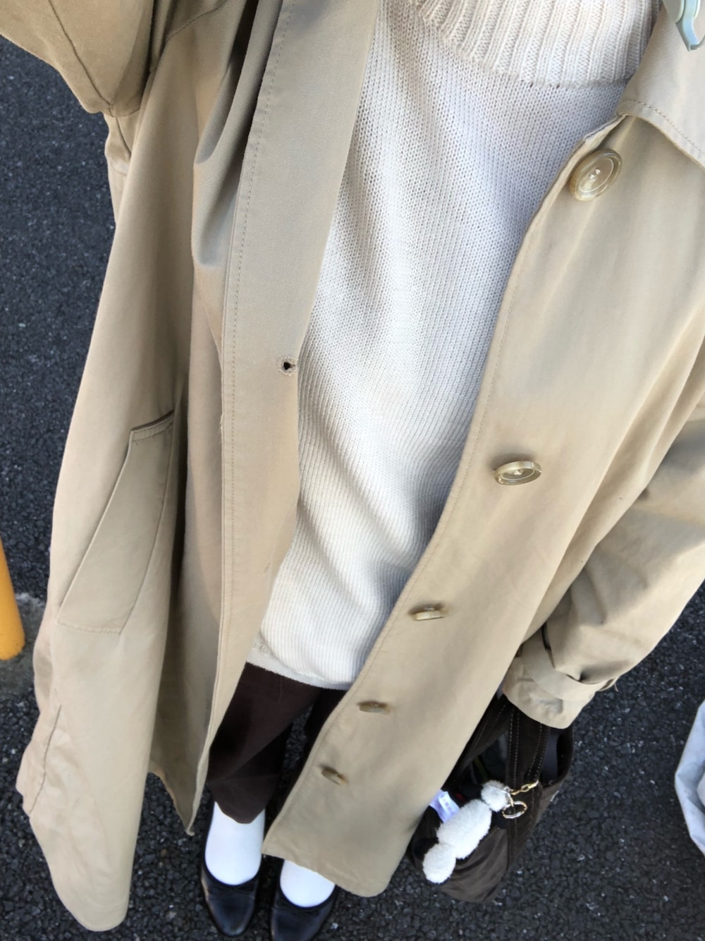 ベージュ系のステンカラーコート、ホワイト系のニット/セーター、ブラウン系のその他パンツを着用したレディースの秋コーディネートの1枚目の写真