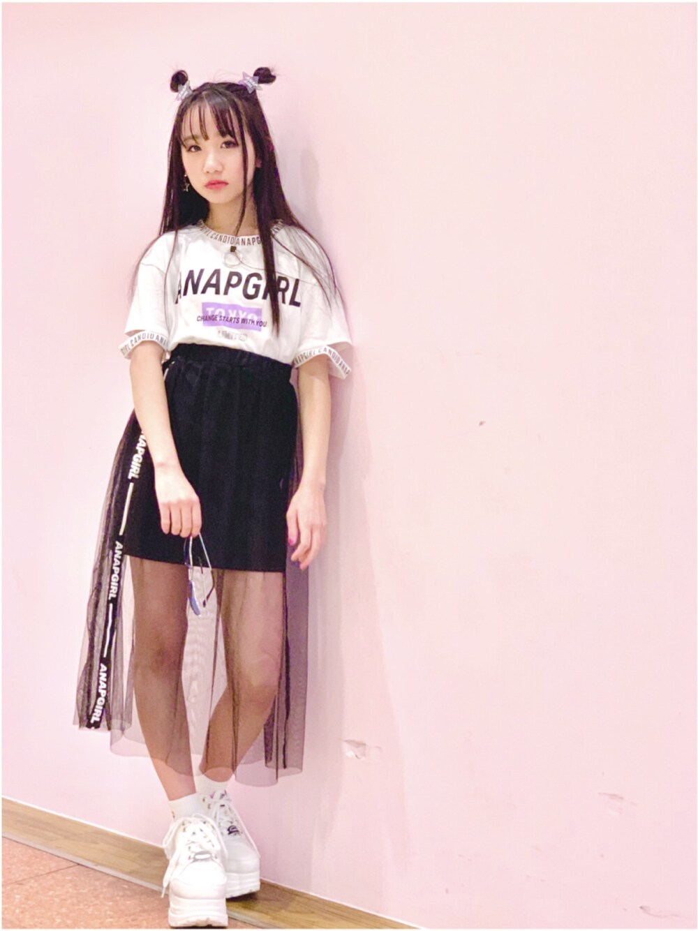 ブラック系のスカート、ホワイト系のTシャツ/カットソー、ホワイト系のスニーカーを着用したレディースの春コーディネートの1枚目の写真