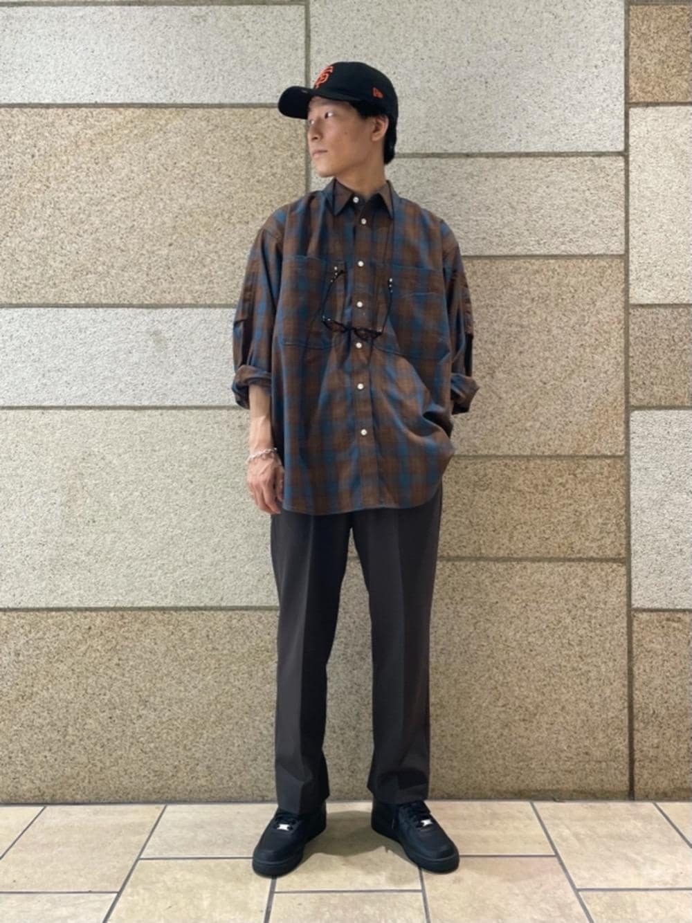 ベージュ系のTシャツ/カットソー、ブラウン系のスラックス、ブラック系のスニーカーを着用したメンズの夏コーディネートの1枚目の写真