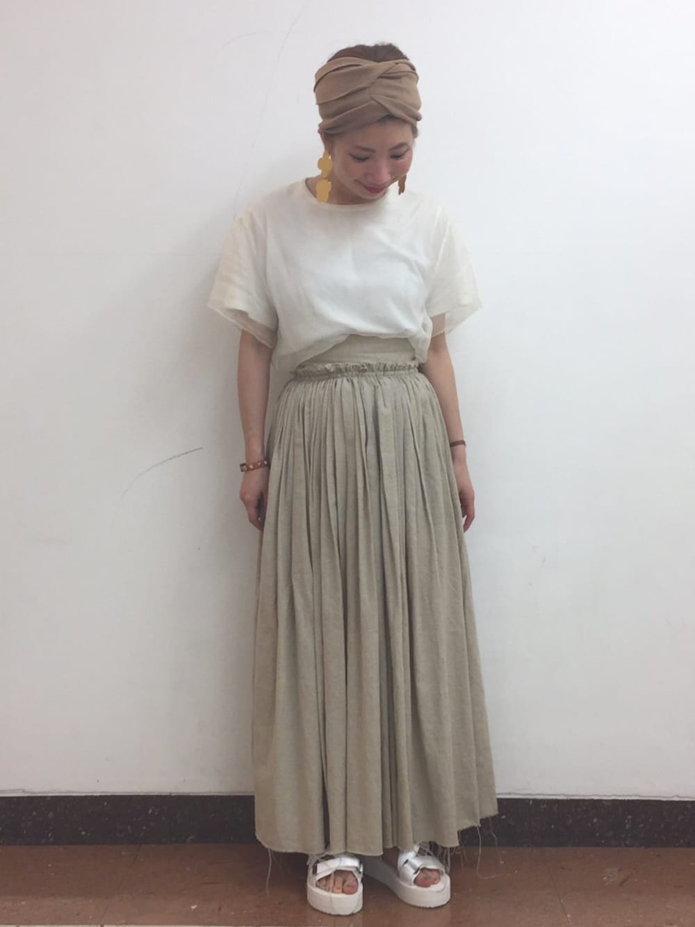 ホワイト系のTシャツ/カットソー、ベージュ系のスカート、ホワイト系のサンダルを着用したレディースの春コーディネートの1枚目の写真
