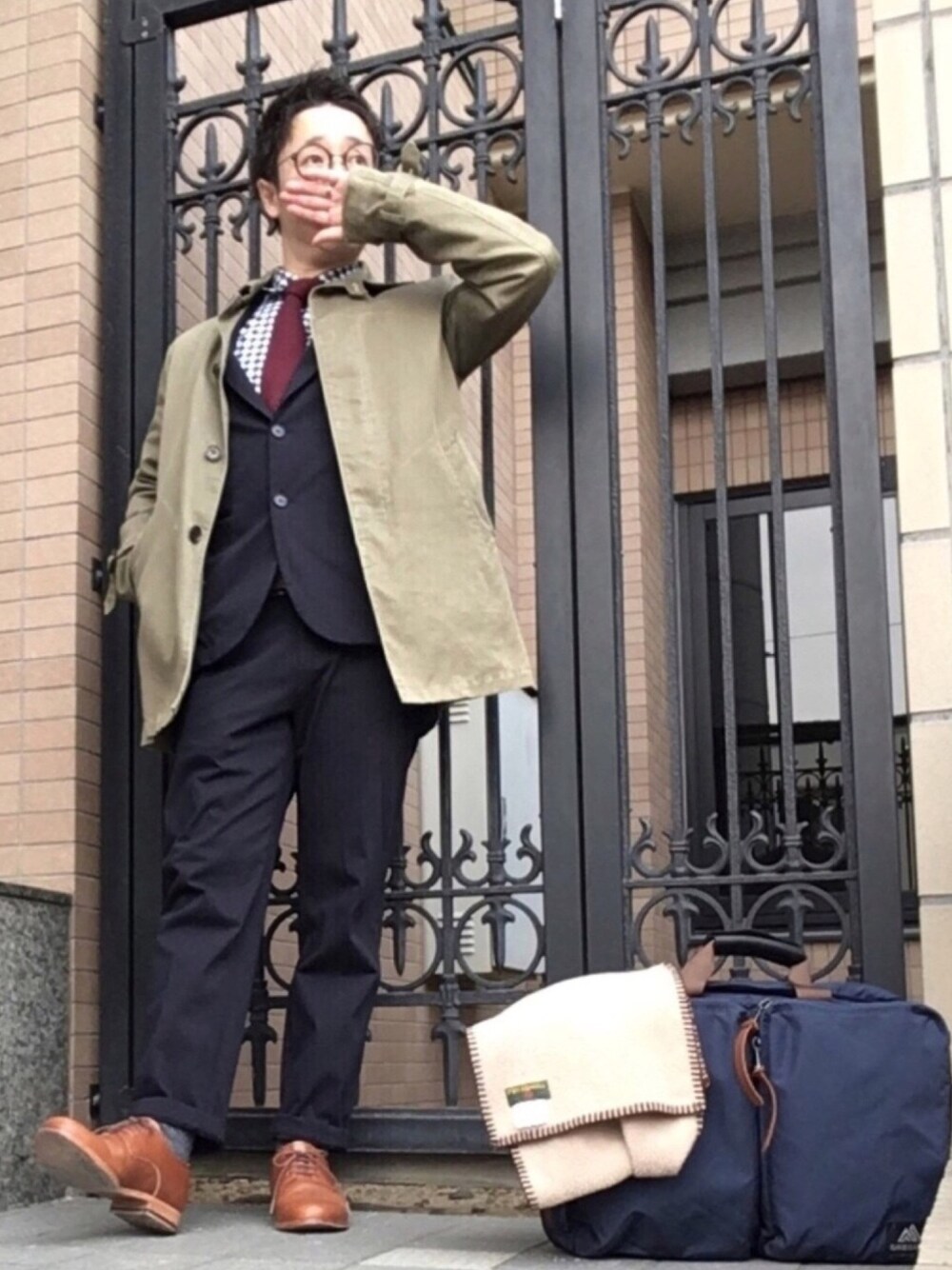 ブラウン系のドレスシューズ、ブルー系のビジネスバッグ、ブルー系のその他パンツを着用したメンズの冬コーディネートの1枚目の写真