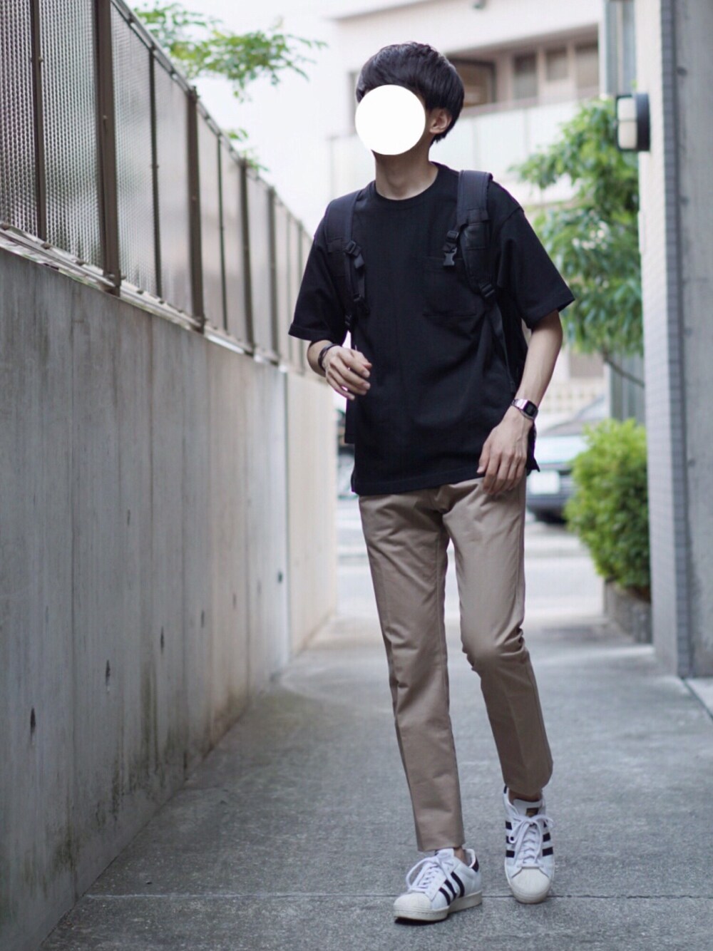 ホワイト系のスニーカー、ブラック系のTシャツ/カットソー、ベージュ系のチノパンツを着用したメンズの夏コーディネートの1枚目の写真