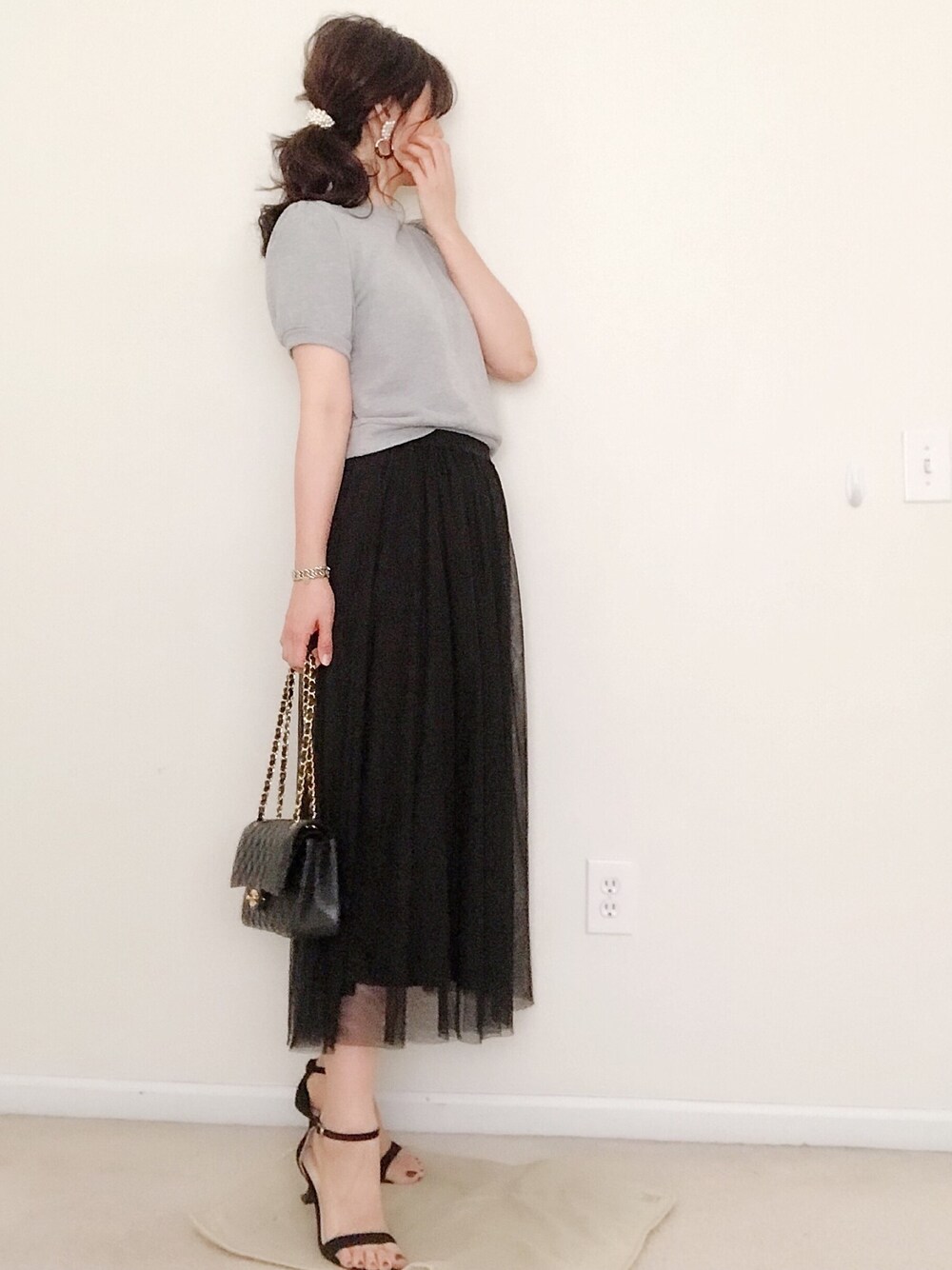 ブラック系のスカートを着用したレディースの春コーディネートの1枚目の写真