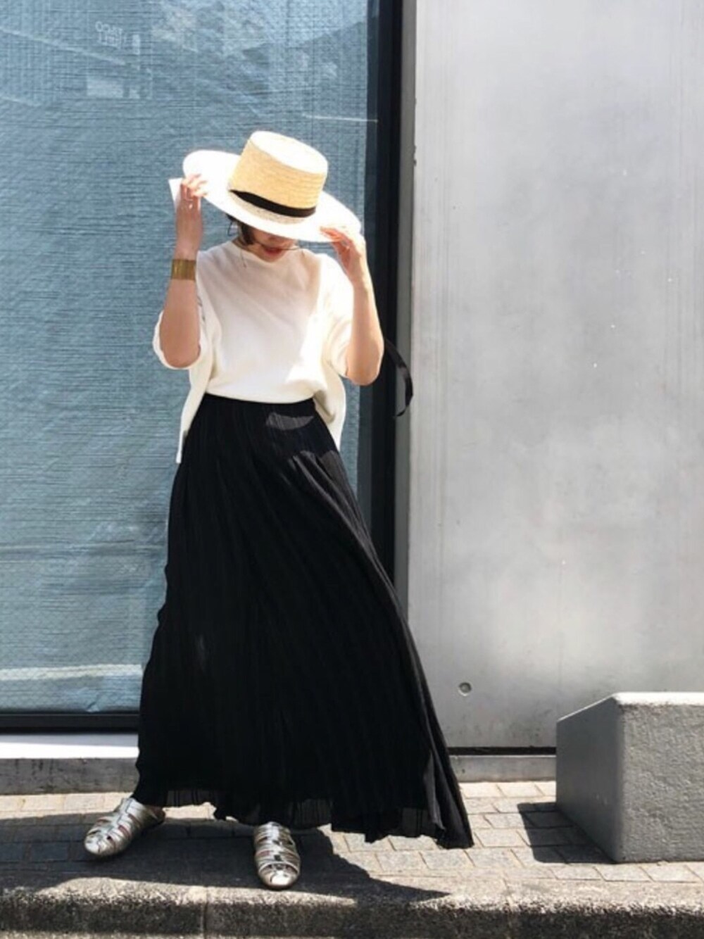 ホワイト系のTシャツ/カットソー、ブラック系のスカート、ゴールド系のサンダルを着用したレディースの春コーディネートの1枚目の写真