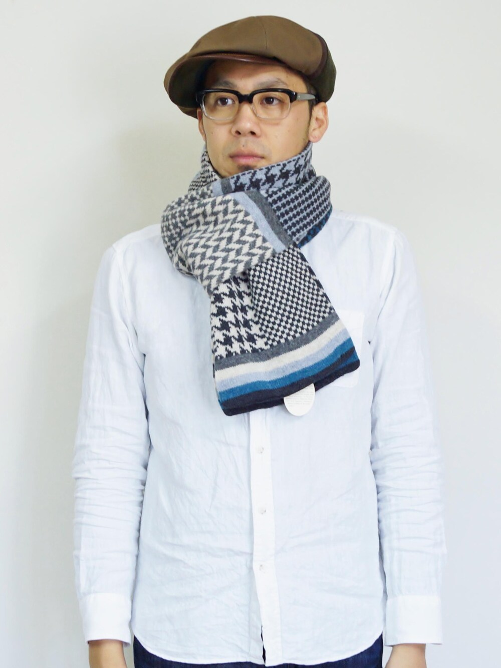 ブルー系のマフラー、グリーン系のキャスケットを着用したメンズの秋コーディネートの1枚目の写真