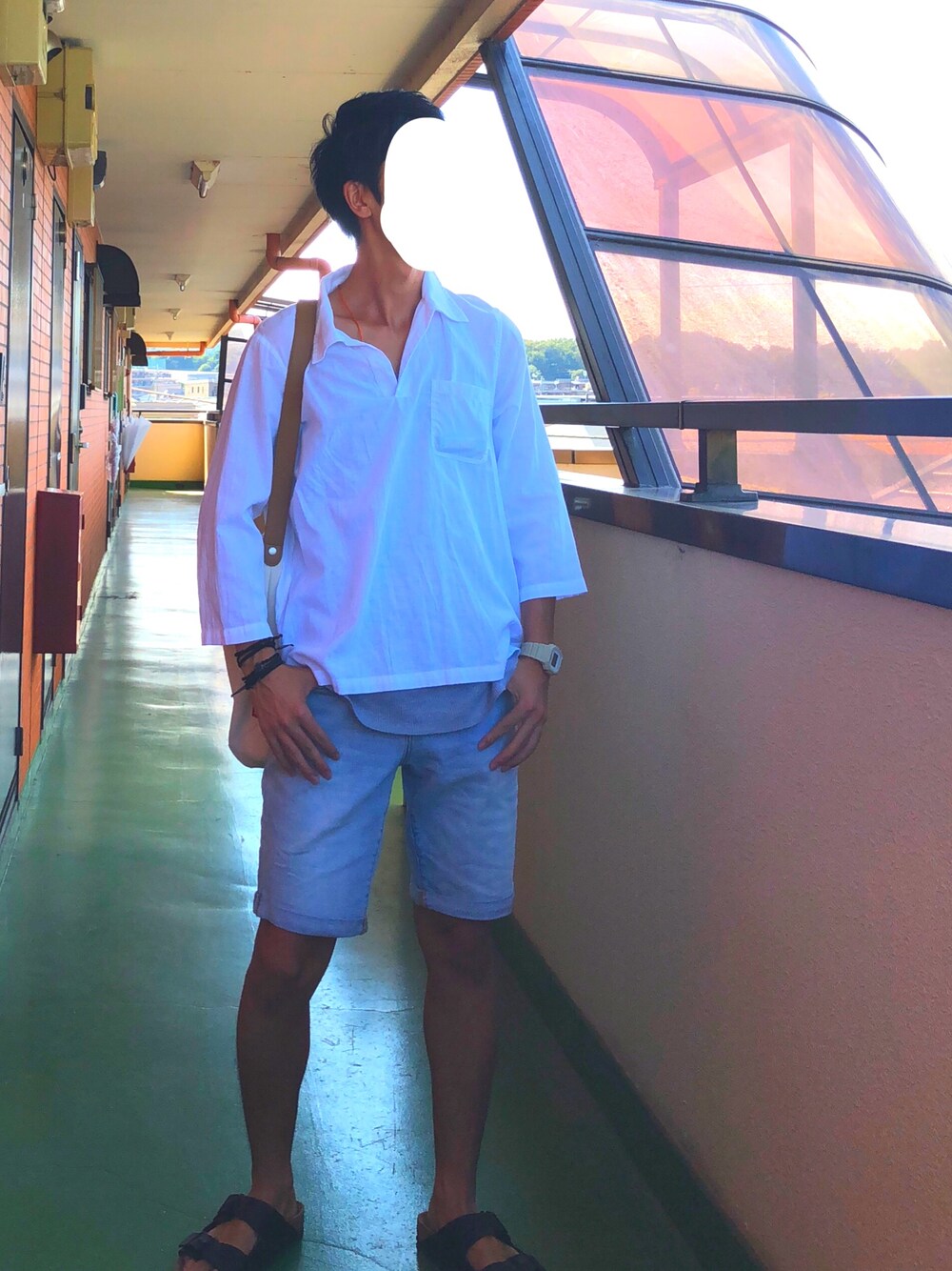 ホワイト系のショルダーバッグ、ブルー系のデニムパンツ、ブラック系のサンダルを着用したメンズの秋コーディネートの1枚目の写真