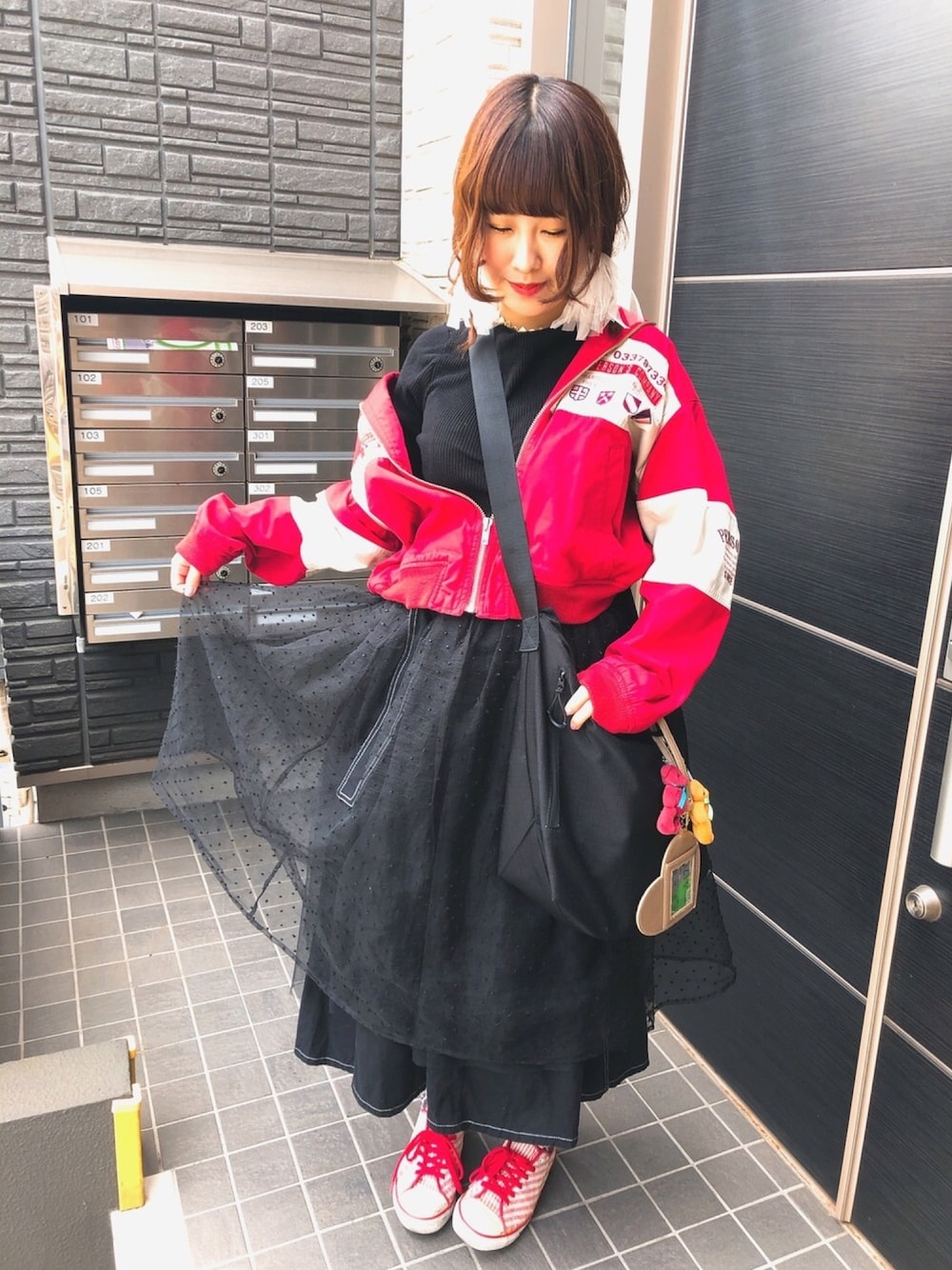 レッド系のマウンテンパーカー、ブラック系のスカート、ブラック系のスカートを着用したレディースの春コーディネートの1枚目の写真