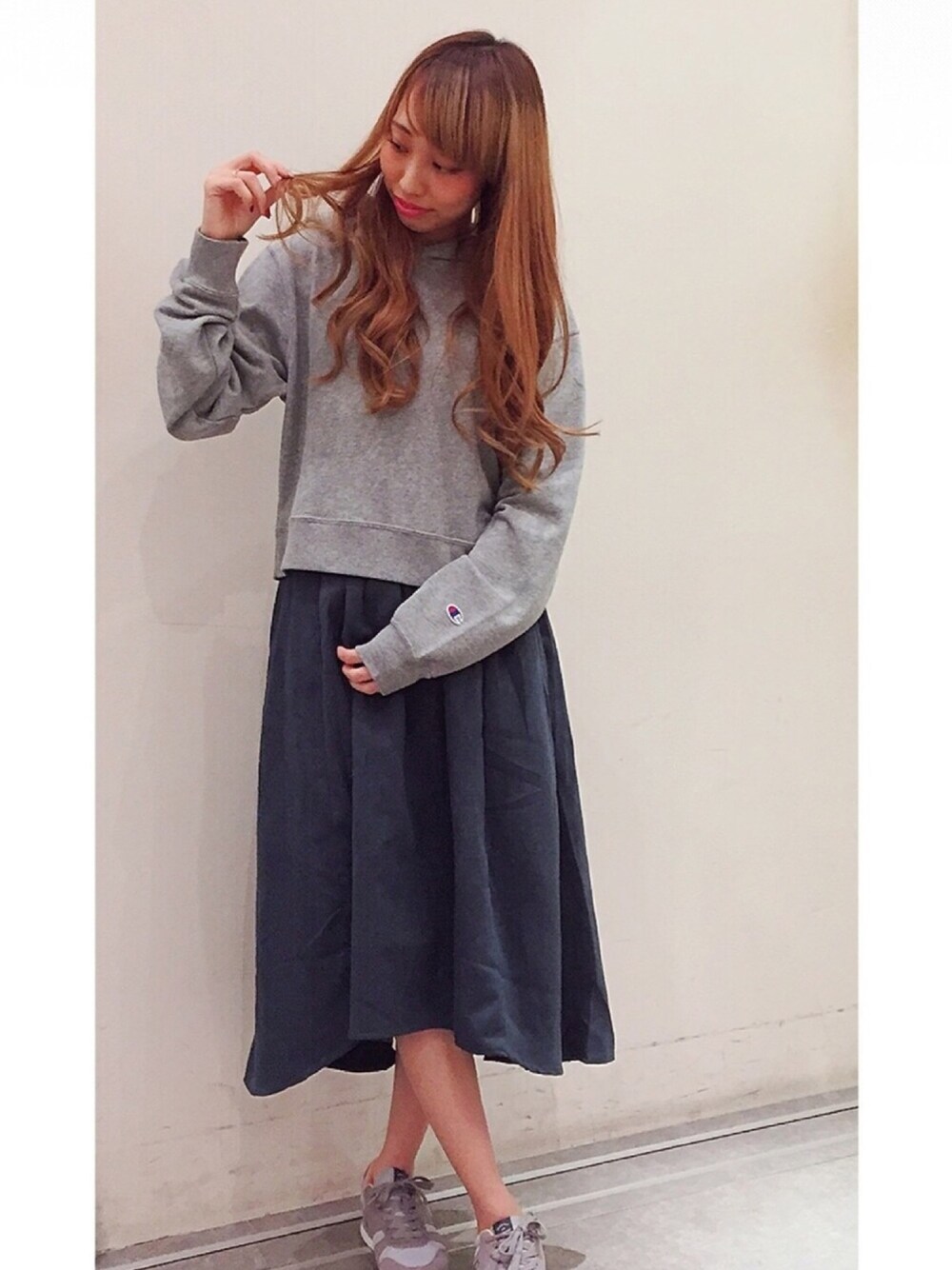 グレー系のパーカー、ブルー系のスカート、グレー系のスニーカーを着用したレディースの秋コーディネートの1枚目の写真