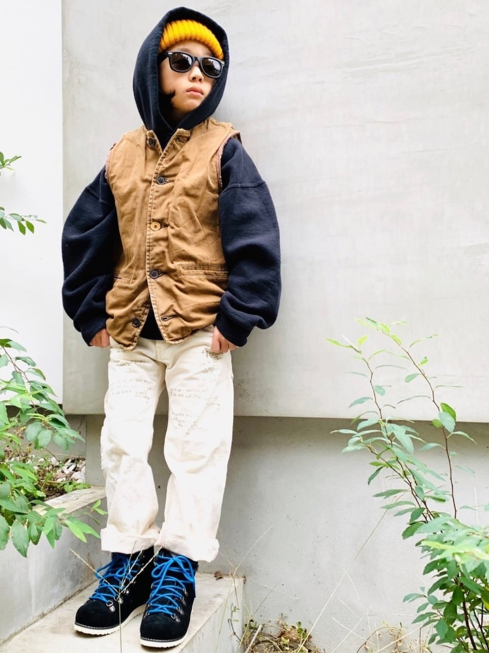 ブラウン系のベスト、オレンジ系のニットキャップ/ビーニーを着用したキッズの冬コーディネートの1枚目の写真