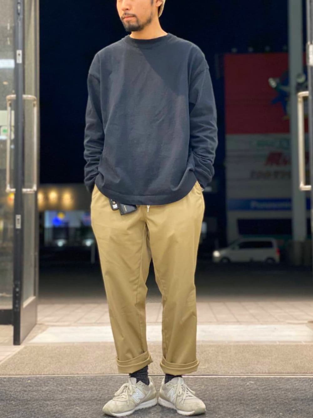 ブラック系のTシャツ/カットソー、ベージュ系のチノパンツ、ホワイト系のスニーカーを着用したメンズの春コーディネートの1枚目の写真