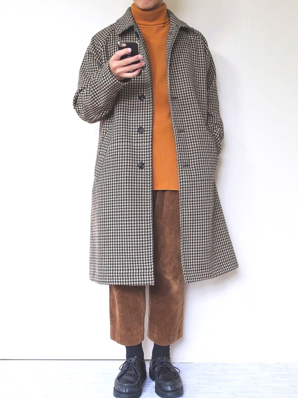 ブラウン系のステンカラーコート、イエロー系のニット/セーター、ブラウン系のその他パンツを着用したメンズの冬コーディネートの1枚目の写真