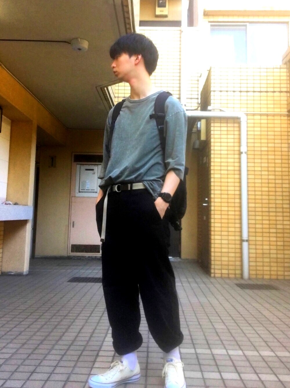 グリーン系のTシャツ/カットソー、ブラック系のバックパック/リュック、ブラック系のパンツを着用したメンズの夏コーディネートの1枚目の写真