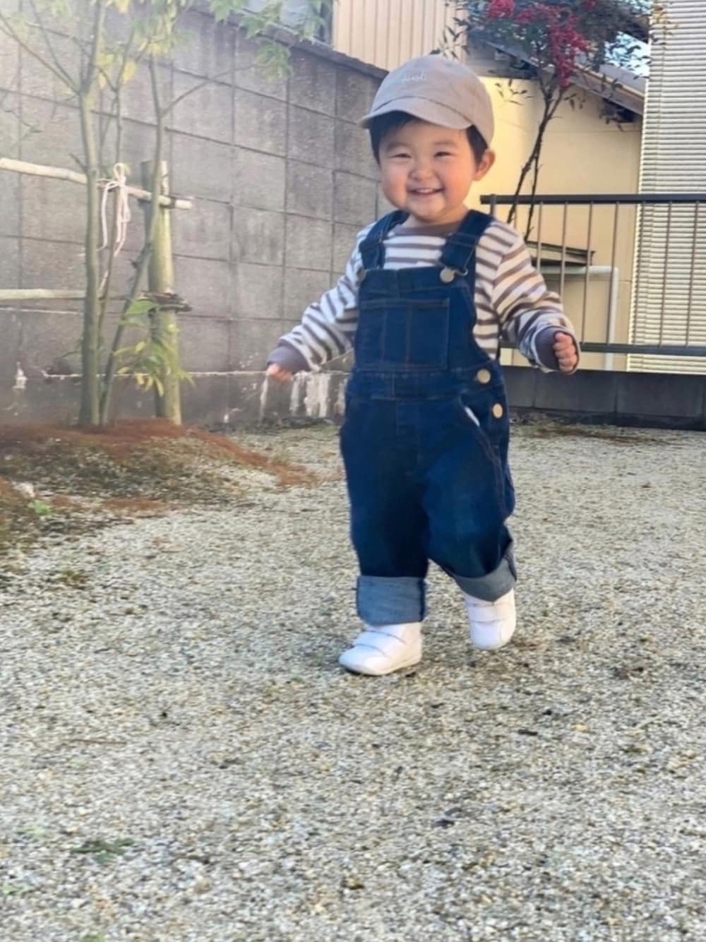 ブルー系のサロペット/オーバーオール、ブラウン系のTシャツ/カットソー、ホワイト系のスニーカーを着用したキッズの冬コーディネートの1枚目の写真