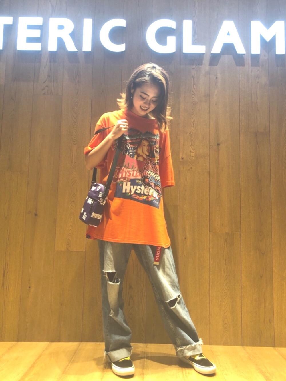 ブルー系のデニムパンツ、オレンジ系のTシャツ/カットソー、パープル系のボディバッグ/ウエストポーチを着用したレディースの夏コーディネートの1枚目の写真