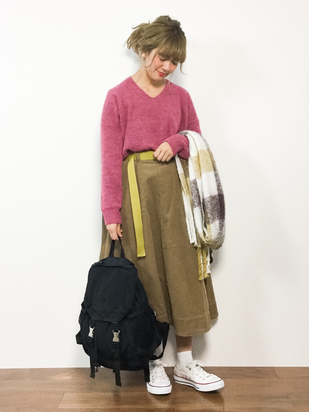 ピンク系のニット/セーター、ベージュ系のスカート、イエロー系のストール/ショールを着用したレディースの冬コーディネートの1枚目の写真