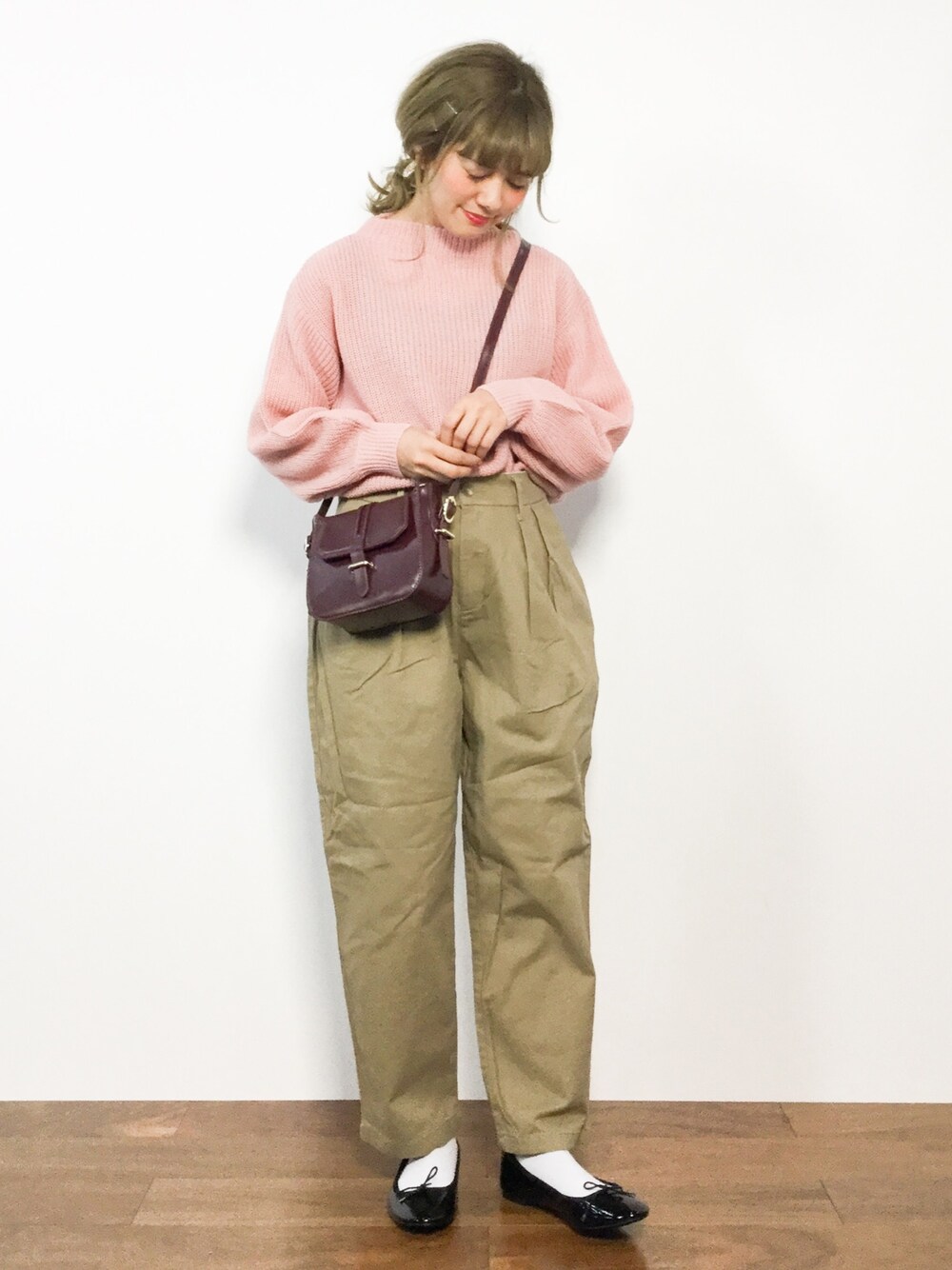 ピンク系のニット/セーター、ベージュ系のチノパンツ、ブラウン系のショルダーバッグを着用したレディースの冬コーディネートの1枚目の写真
