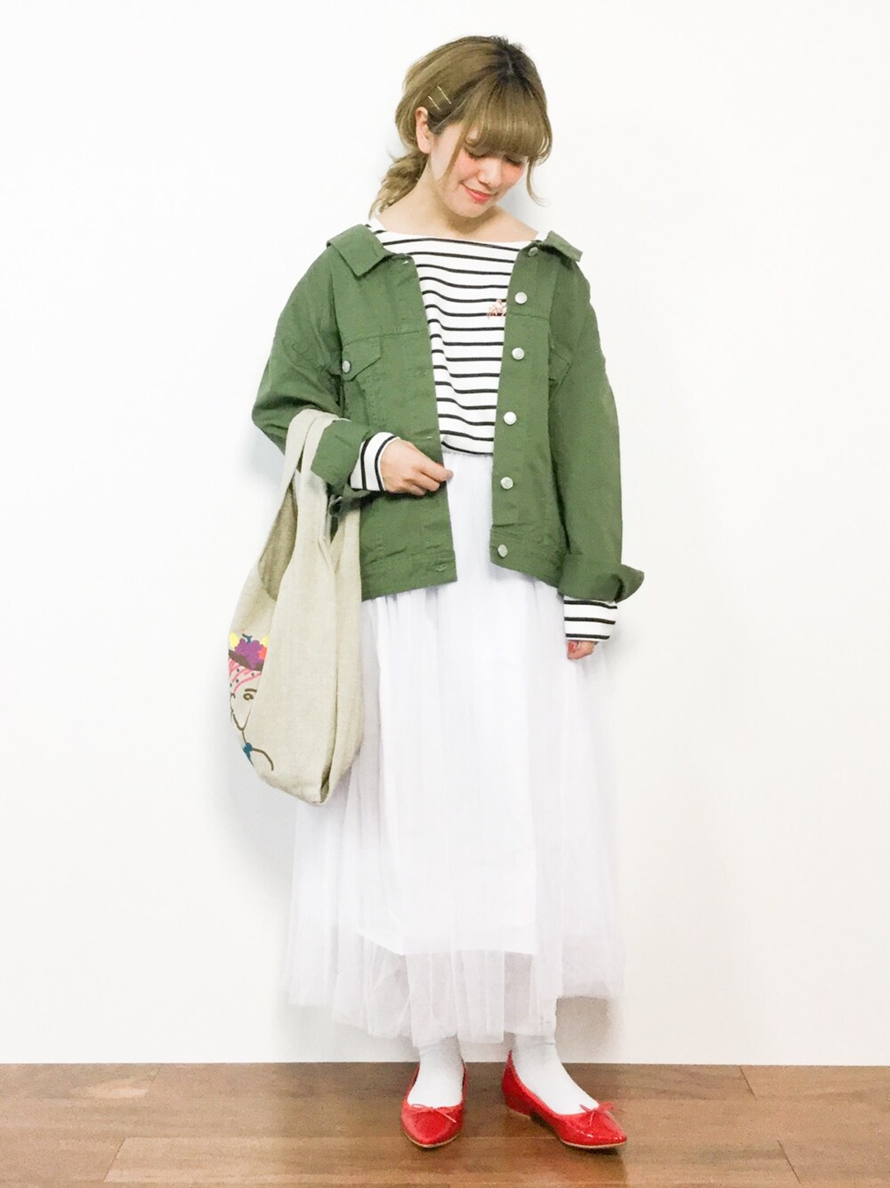ホワイト系のTシャツ/カットソー、グリーン系のミリタリージャケット、ホワイト系のスカートを着用したレディースの冬コーディネートの1枚目の写真