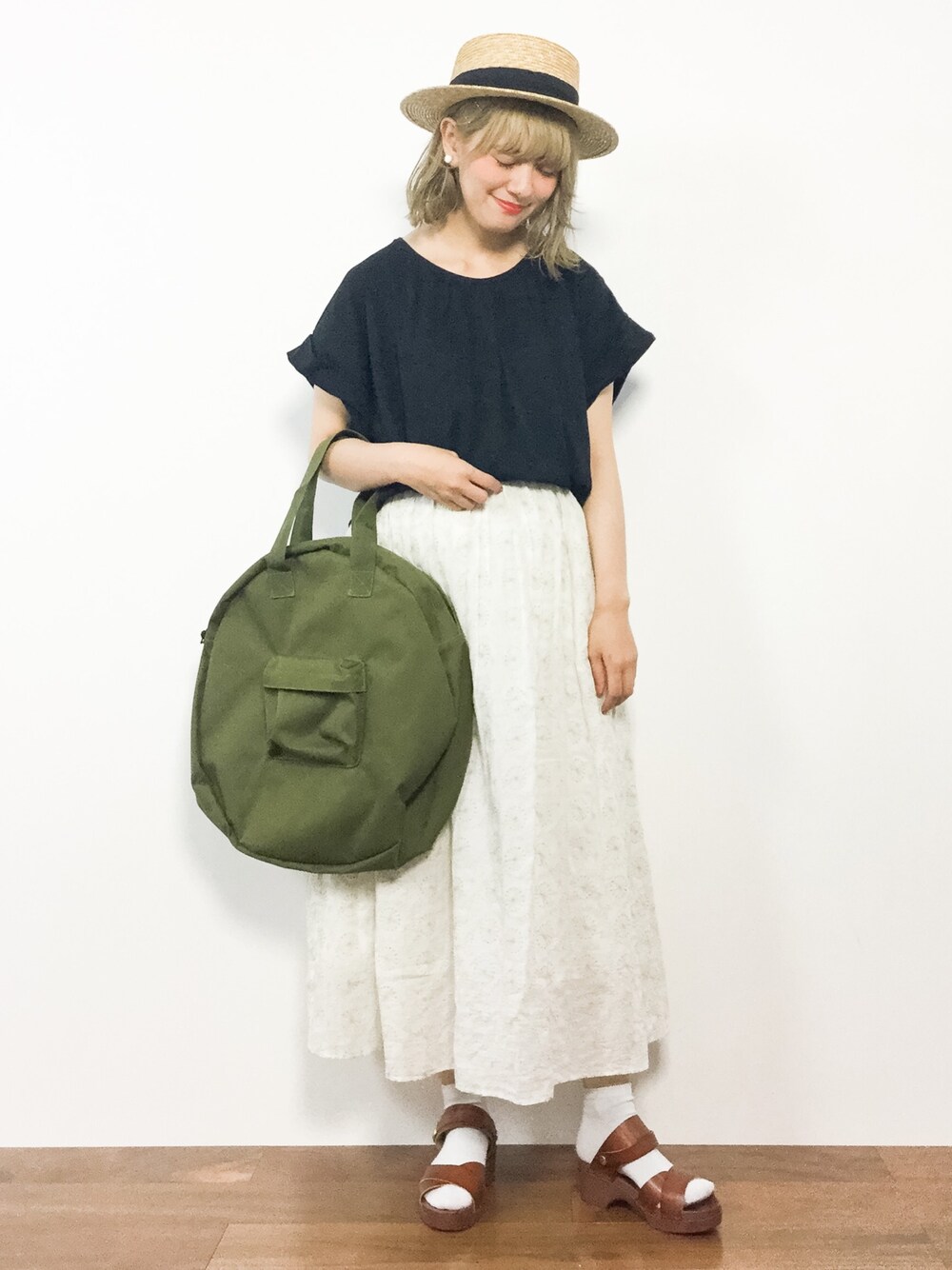 ブラック系のTシャツ/カットソー、ホワイト系のスカート、グリーン系のトートバッグを着用したレディースの夏コーディネートの1枚目の写真