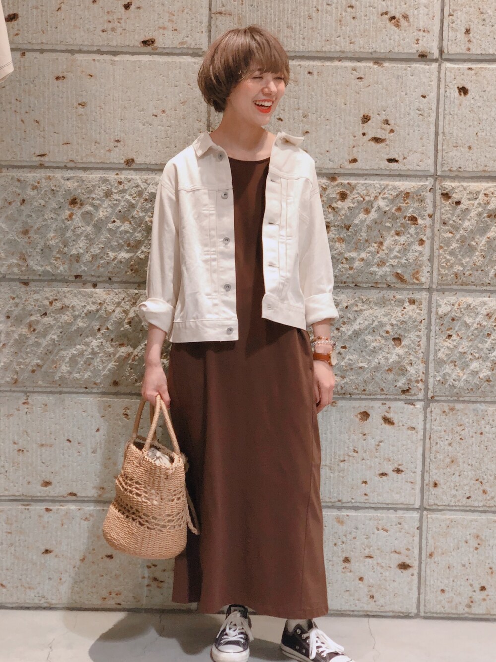 ブルー系のデニムジャケット、ブラウン系のワンピース、ブラック系のスニーカーを着用したレディースの春コーディネートの1枚目の写真