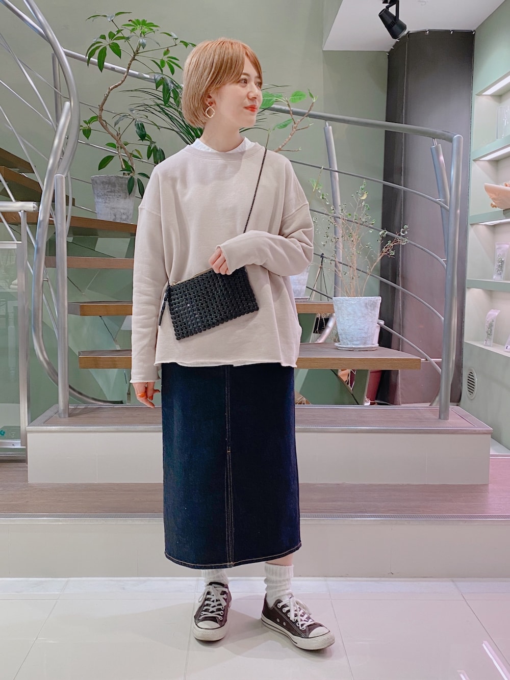 ピンク系のスウェット、ブルー系のデニムスカート、ブラック系のスニーカーを着用したレディースの春コーディネートの1枚目の写真