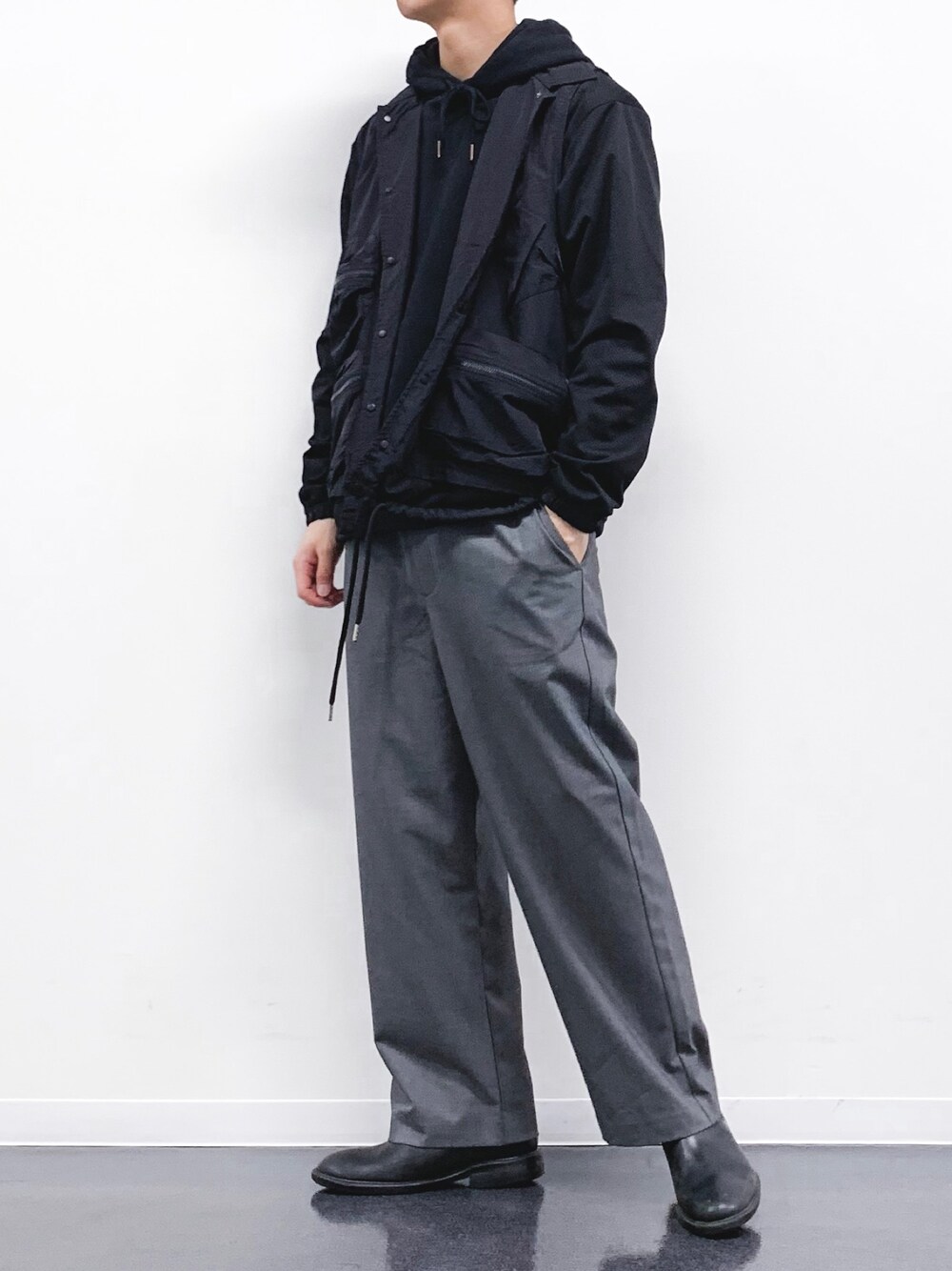 ブラック系のその他アウター、ブラック系のパーカー、グレー系のスラックスを着用したメンズの冬コーディネートの1枚目の写真