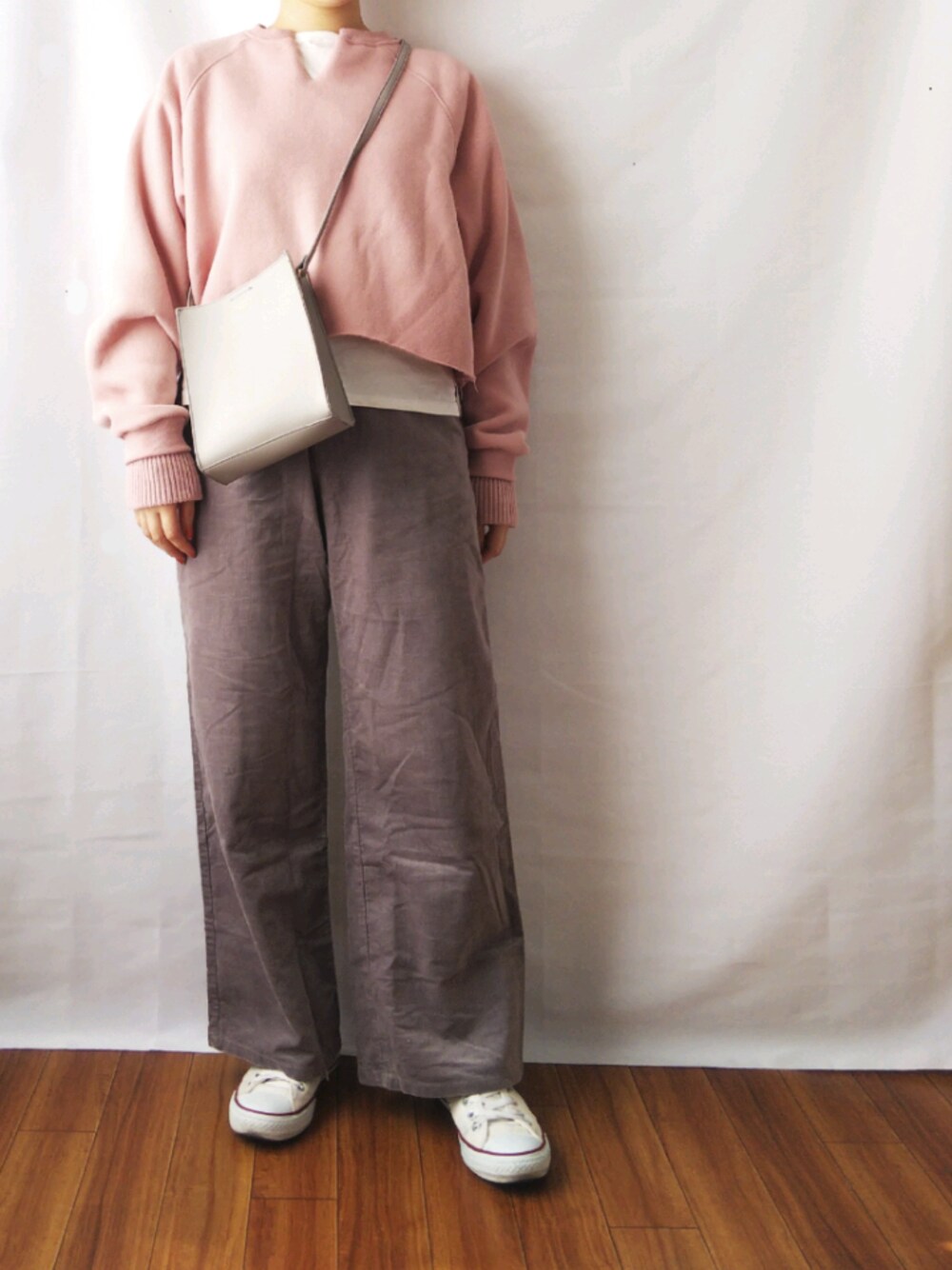 ピンク系のスウェット、グレー系のパンツ、グレー系のショルダーバッグを着用したレディースの春コーディネートの1枚目の写真