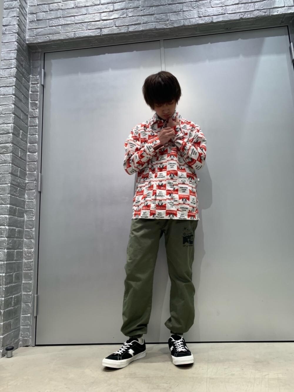 ブラック系のスニーカー、レッド系のカバーオール、グリーン系のカーゴパンツを着用したメンズの秋コーディネートの1枚目の写真