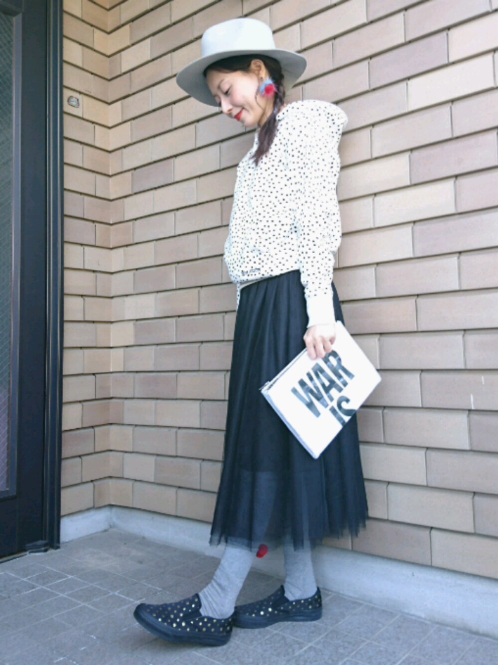 ホワイト系のクラッチバッグ、ブラック系のスカート、ブラック系のスニーカーを着用したレディースの冬コーディネートの1枚目の写真