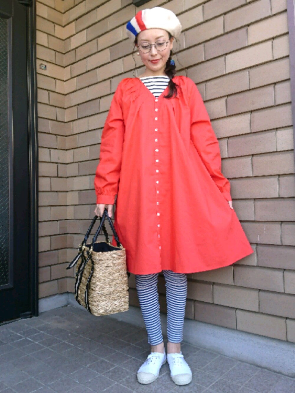 ホワイト系のスニーカー、レッド系のワンピース、ブラック系のかごバッグを着用したレディースの春コーディネートの1枚目の写真