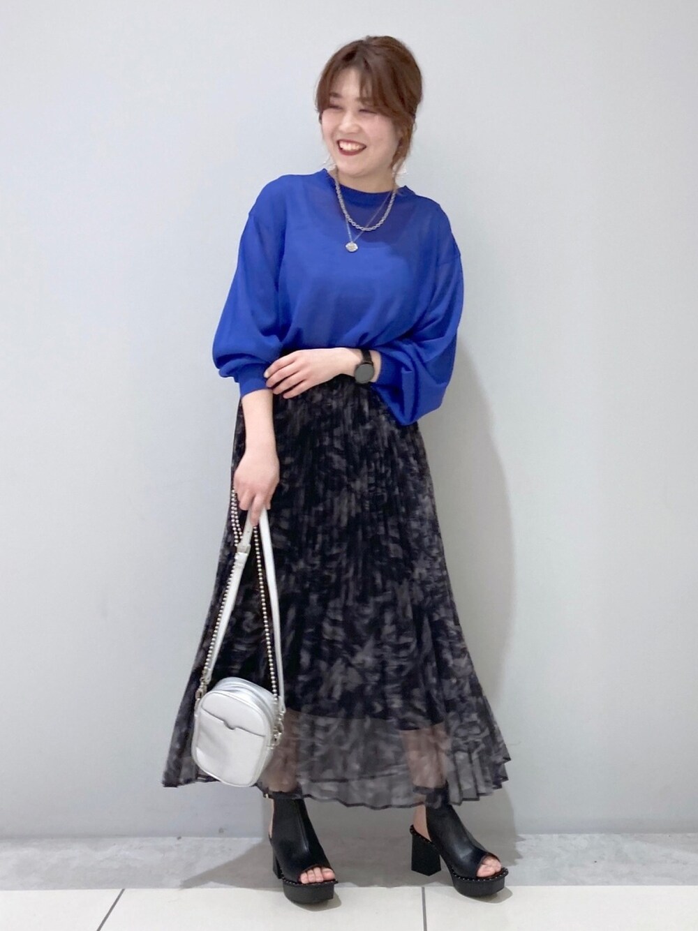 ブルー系のニット/セーター、ホワイト系のタンクトップ、ブラック系のスカートを着用したレディースの春コーディネートの1枚目の写真