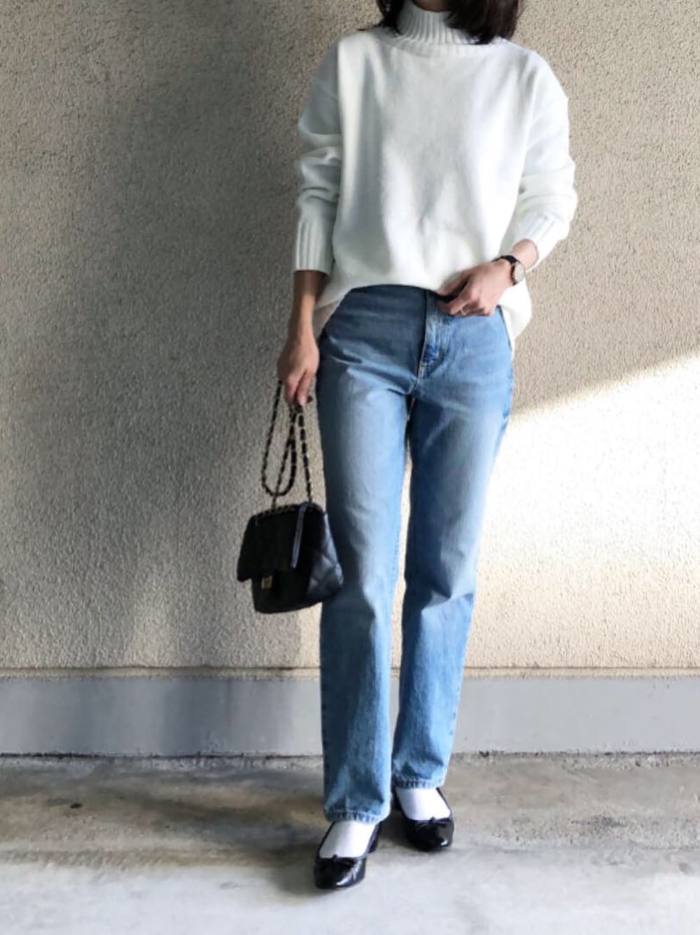 ブラック系のショルダーバッグ、ホワイト系のニット/セーター、ブラック系のアナログ腕時計を着用したレディースの冬コーディネートの1枚目の写真