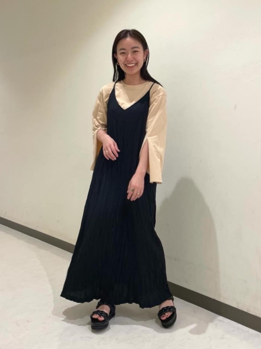 ブラック系のワンピース、ベージュ系のTシャツ/カットソーを着用したレディースの春コーディネートの1枚目の写真