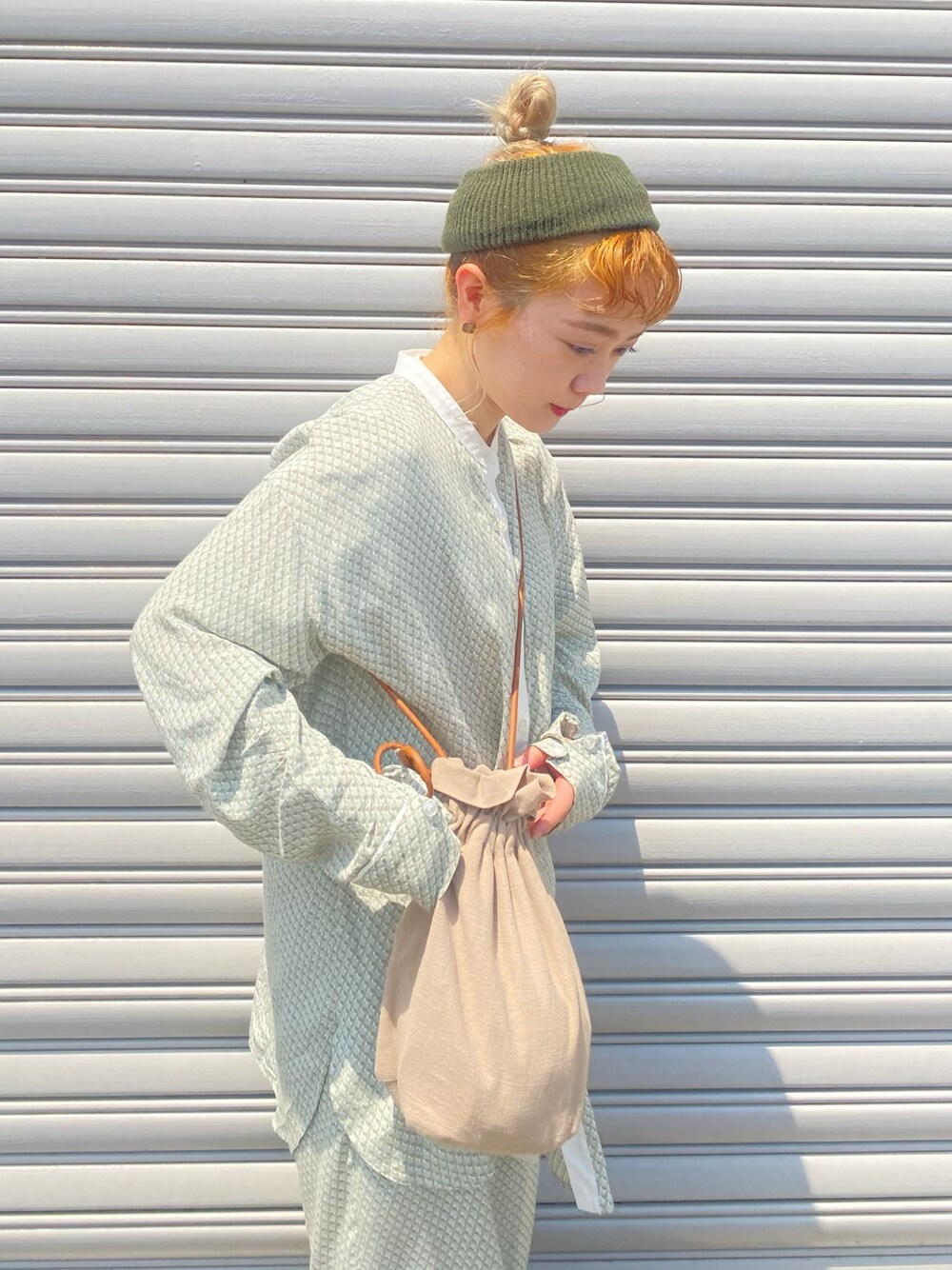 グリーン系のトップス、グリーン系のパンツ、ベージュ系のショルダーバッグを着用したレディースの春コーディネートの1枚目の写真