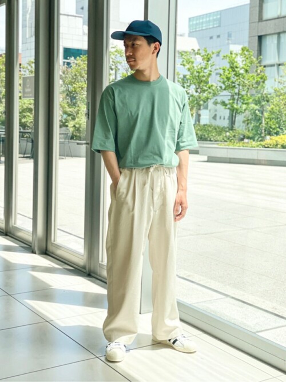 グリーン系のTシャツ/カットソー、ホワイト系のその他パンツ、グレー系のキャップを着用したメンズの春コーディネートの1枚目の写真