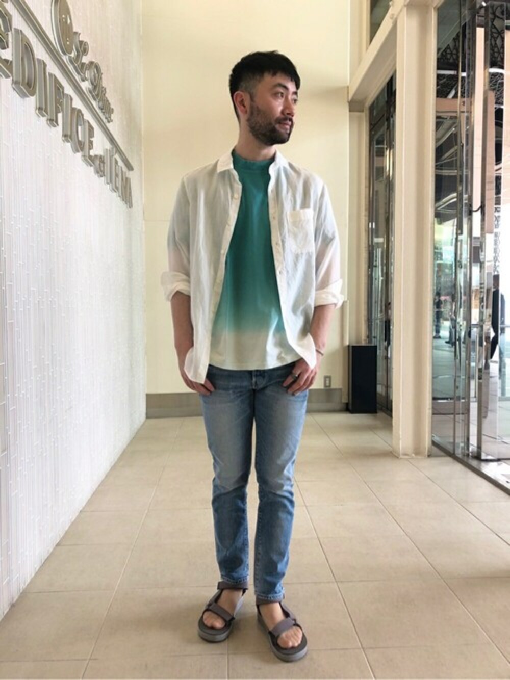 ホワイト系のシャツ/ブラウス、ブルー系のデニムパンツ、グレー系のサンダルを着用したメンズの夏コーディネートの1枚目の写真