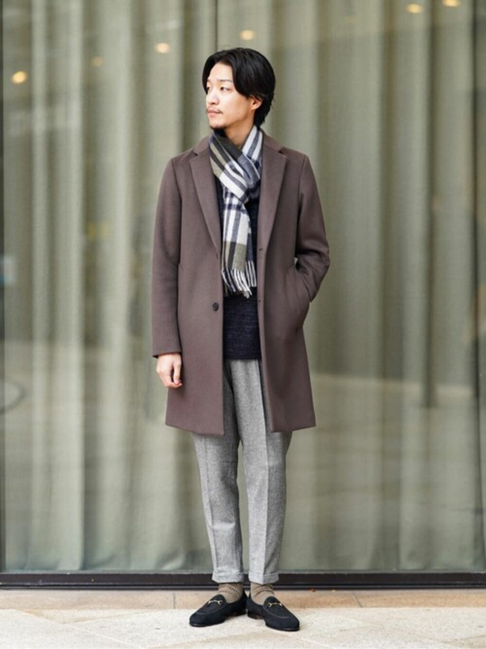 ブラウン系のチェスターコート、ブラック系のニット/セーター、グレー系のその他パンツを着用したメンズの冬コーディネートの1枚目の写真