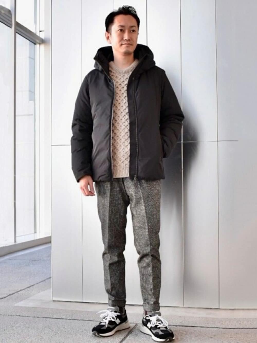 ブラック系のダウンジャケット/コート、ベージュ系のニット/セーター、ブラック系のスラックスを着用したメンズの冬コーディネートの1枚目の写真