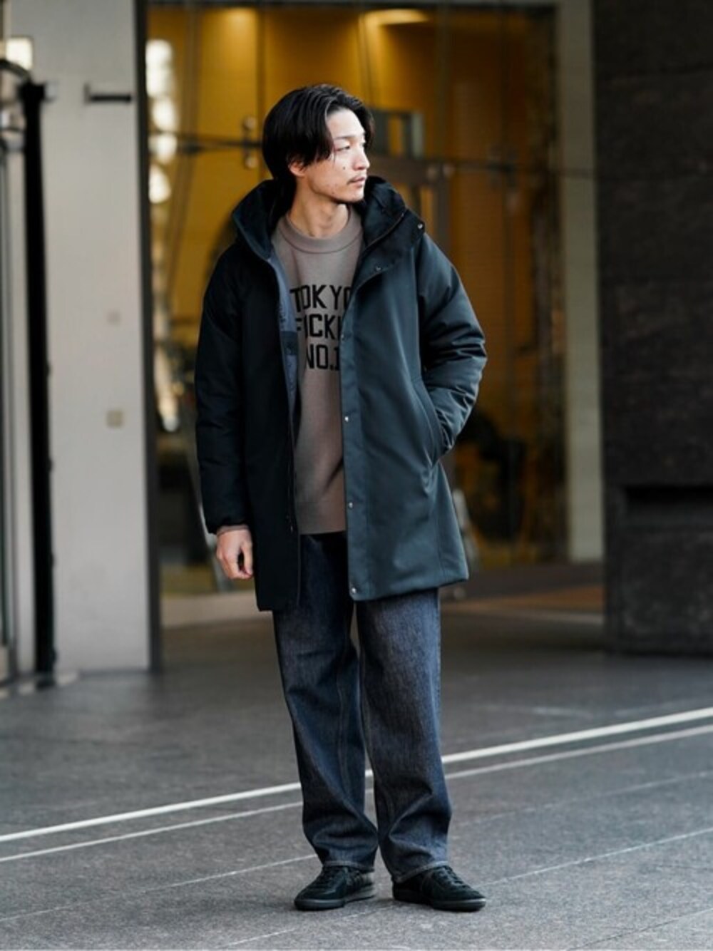 ブラック系のダウンジャケット/コート、ブラウン系のニット/セーター、ブラック系のスニーカーを着用したメンズの冬コーディネートの1枚目の写真