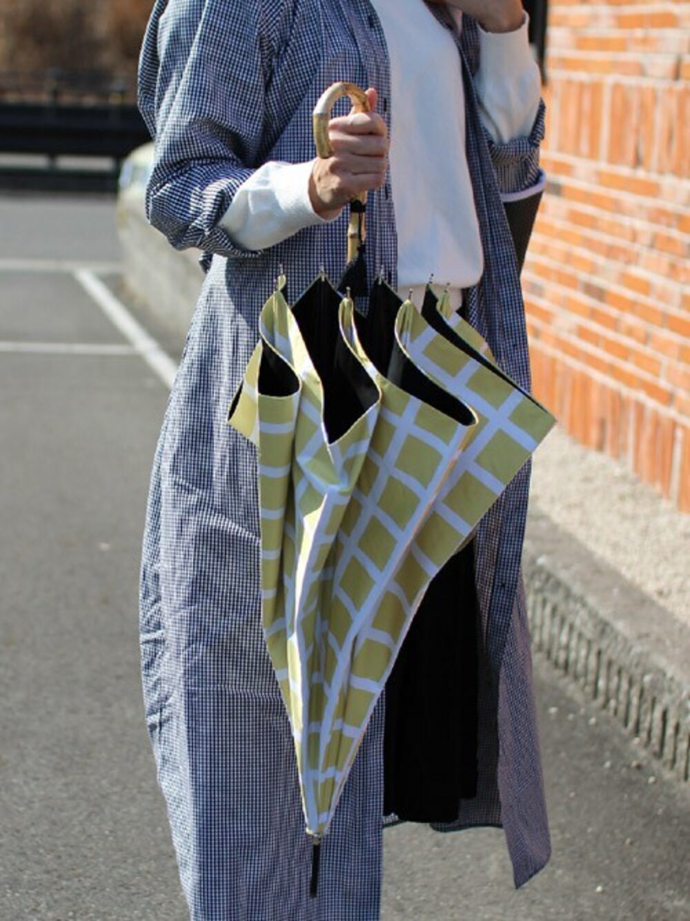 イエロー系の長傘、ブラック系の長傘を着用したレディースの夏コーディネートの1枚目の写真